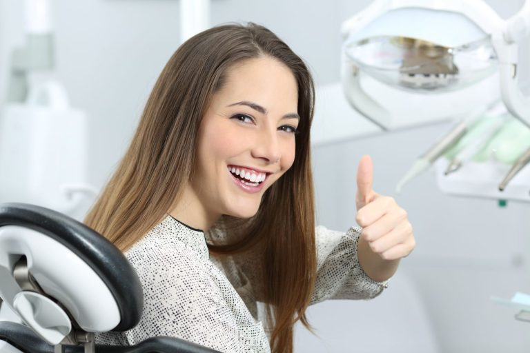 Pacienta de stomatologie fericita la finalul unui tratament prin implant dentar