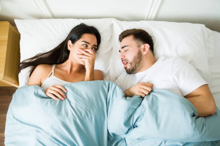 cuplu in pat in timp ce barbatul are o respiratie urat mirositoare